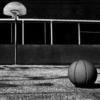 Basketball on outdoor court floor with hoop in background